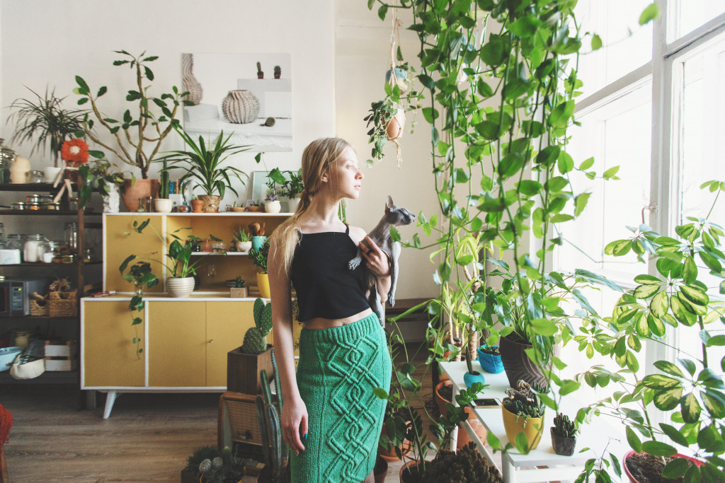 woman with kat inside her house with indoor plants