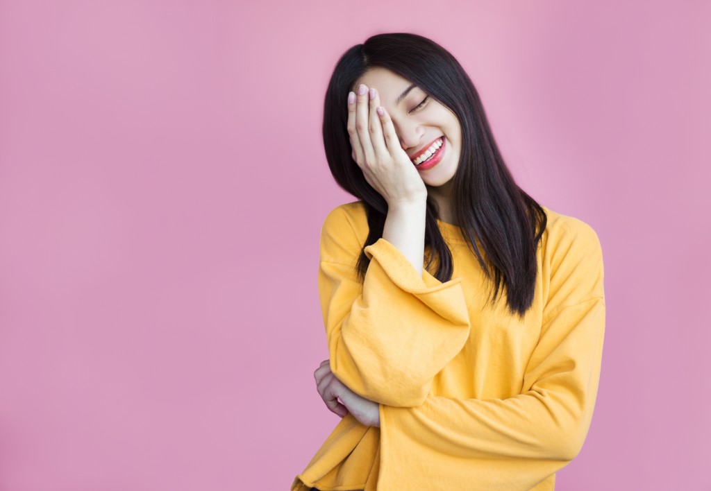 woman smiling with hand covering half her face
