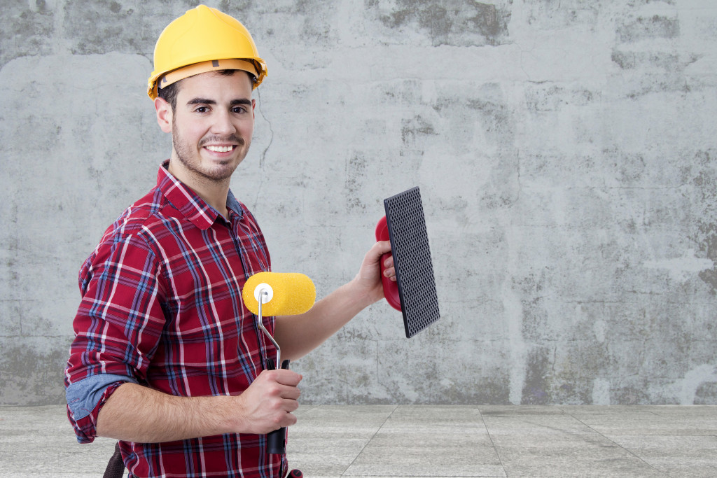 Man holding a paint roller and a trowel