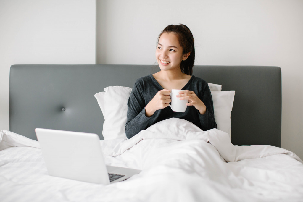 woman laying happy in bed holding coffee