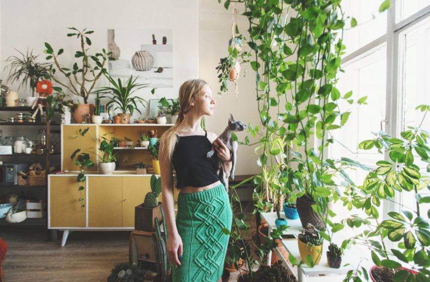 woman holding a cat in a room full of plants