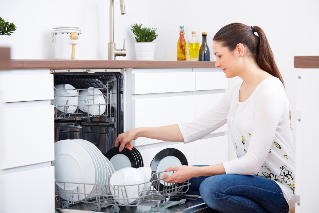 A woman emptying out the dishwasher in a kitchen